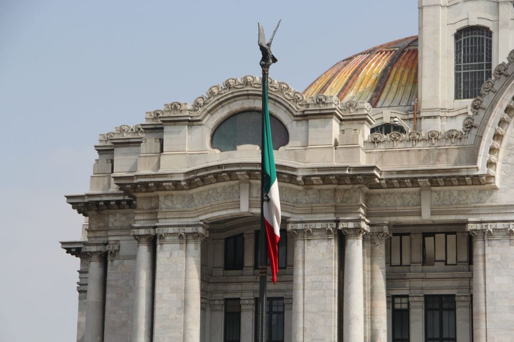 Bandeira da Itália em frente a um edifício histórico com detalhes arquitetônicos e uma cúpula colorida
