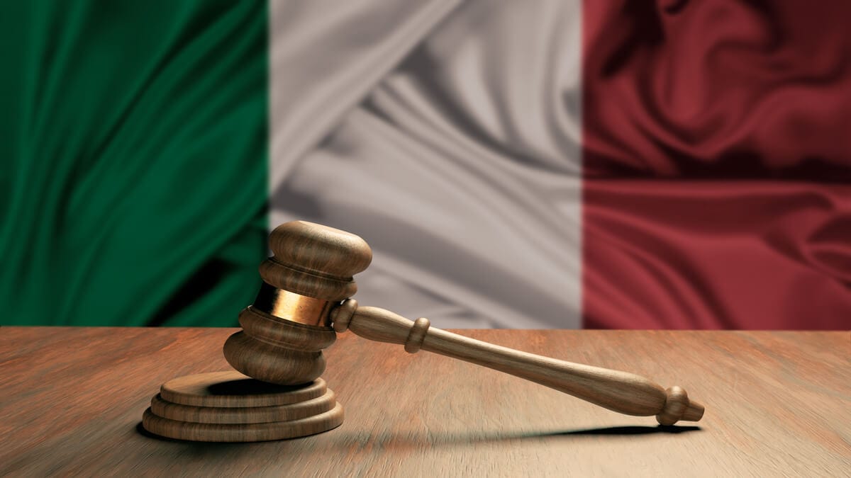 Martelo em tribunal com bandeira italiana ao fundo