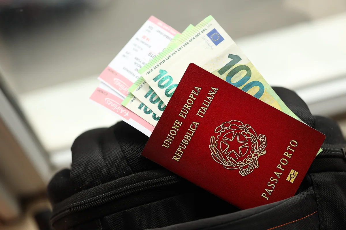 Passaporte italiano com notas de euro e bilhetes de viagem em bolsa preta
