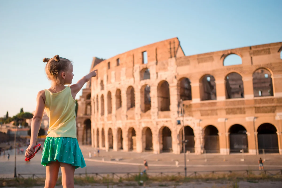 Criança apontando para o Coliseu em Roma durante o pôr do sol