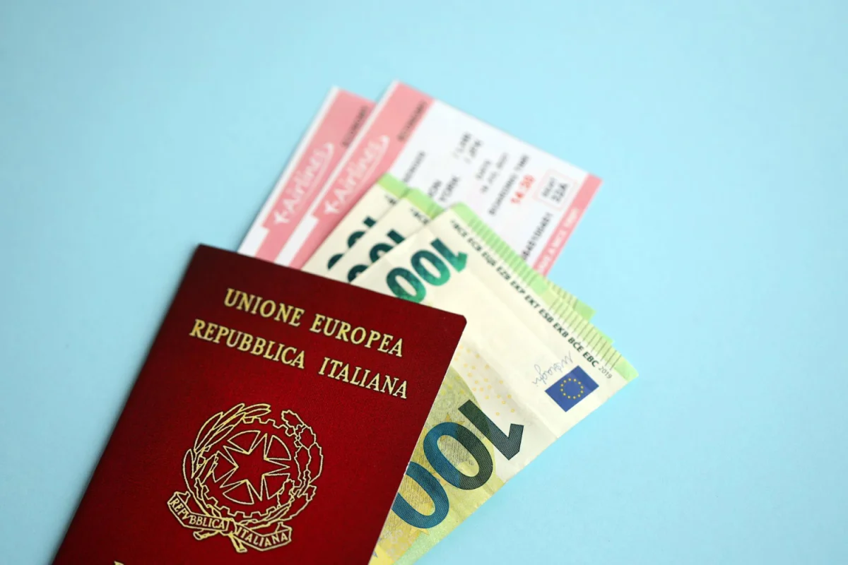Passaporte italiano com cédulas de euro e bilhetes de viagem em fundo azul