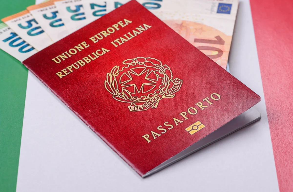 Passaporte italiano vermelho sobre a bandeira da Itália com notas de euro ao fundo