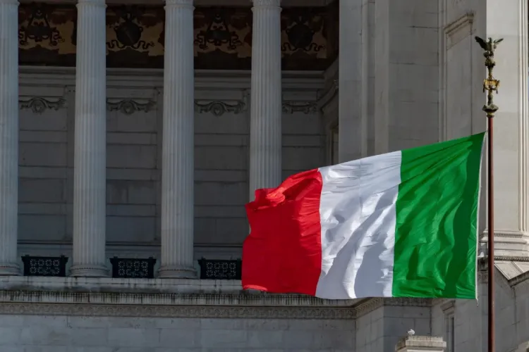 Bandeira da Itália tremulando em frente a um edifício clássico com colunas brancas